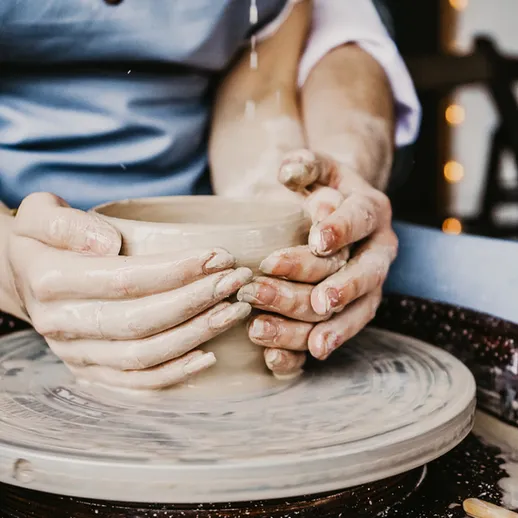 Женщина лепит глиняную посуду на гончарном круге в художественной студии