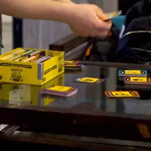 Игроки раскладывают карты на столе в уютной комнате во время вечеринки с друзьями