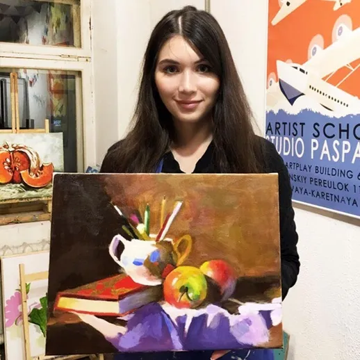 Художница позирует с картиной в художнической школе на выставке в осенний вечер