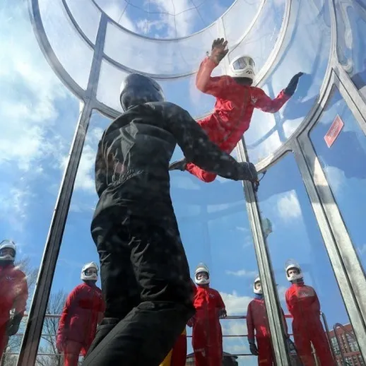 Учебный полет в аэротрубе на открытом воздухе в солнечную погоду с участниками в защитных костюмах