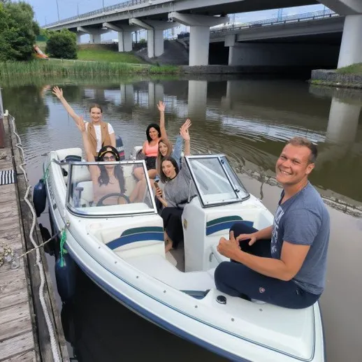 Группа людей на лодке возле моста в спокойной воде в летний день