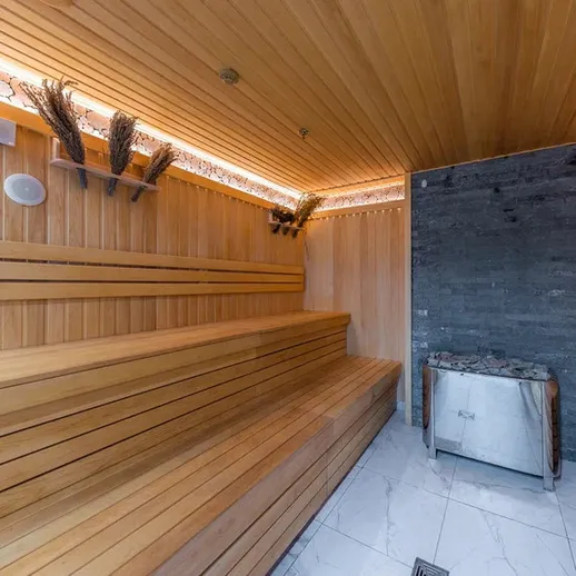Сауна с деревянными полками и каменной стеной, расположенная в уютном пространстве