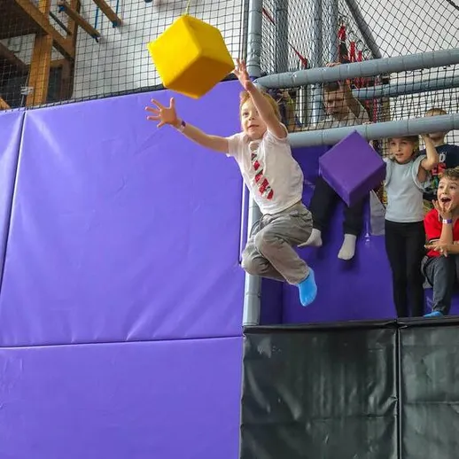 Дети прыгают и играют в батутном центре с мягкими кубами в спортивном зале