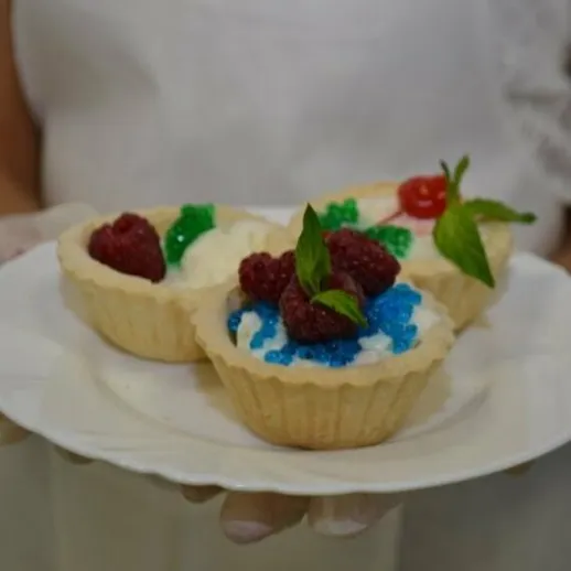 Тарталетки с ягодами и кремом в белом блюде на выставке кулинарии в летнее время