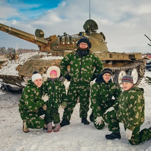 Дети в военной форме позируют с танком на зимнем фоне в лесу