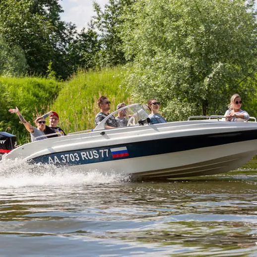 Группа людей на моторной лодке наслаждаются поездкой по реке в солнечный день