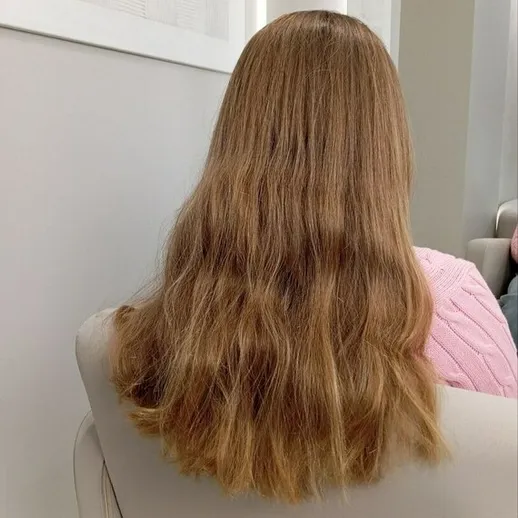 Женщина с длинными волнистыми волосами сидит в уютном интерьере в светлые тона