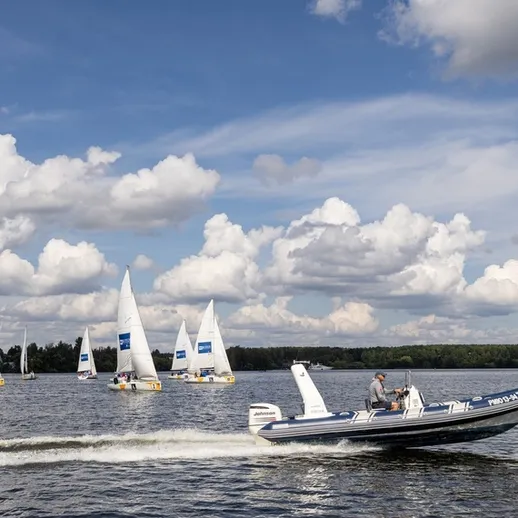 На воде проходят соревнования по парусному спорту с участием катера