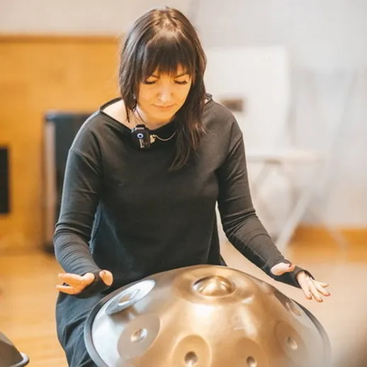 Женщина играет на хандпан в уютном помещении во время музыкального занятия