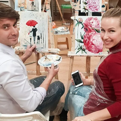 Художники занимаются живописью в студии, создавая яркие картины с цветами и пейзажами в уютной атмосфере