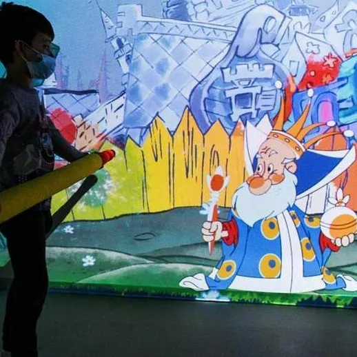 Мальчик с цветным катанием изучает проекцию мультфильма в творческом пространстве