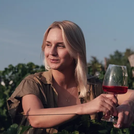 Женщина наслаждается вином на виноградниках в солнечный день летом