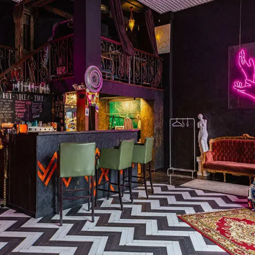 Уютный интерьер кафе с лампами в неоновом свете, стильный бар и оригинальная мебель