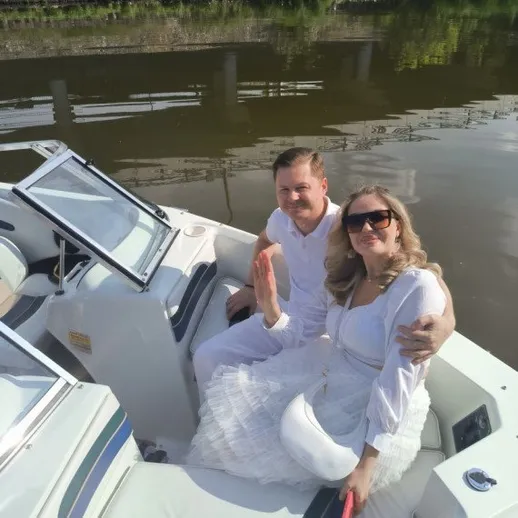 Пара едет на моторной лодке по реке в теплый день в белой одежде