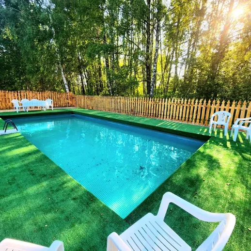 Уютный бассейн на загородном участке среди зелени в теплый солнечный день