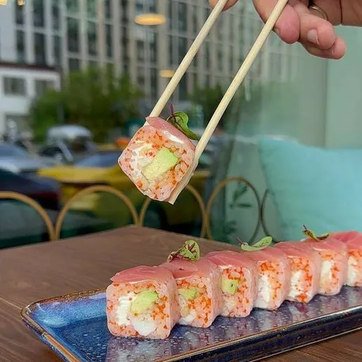 Роллы с лососем и авокадо, поданные на тарелке в кафе, в центре города в солнечный день