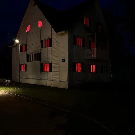 Красивый дом с яркими окнами, освещенный ночным светом, расположенный в тихом районе