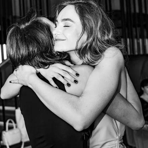 Две женщины обнимаются на вечеринке, выражая радость и дружбу в атмосферном помещении