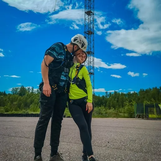 Пара в спортивной одежде на фоне высокой башни связи в ясный день на природе