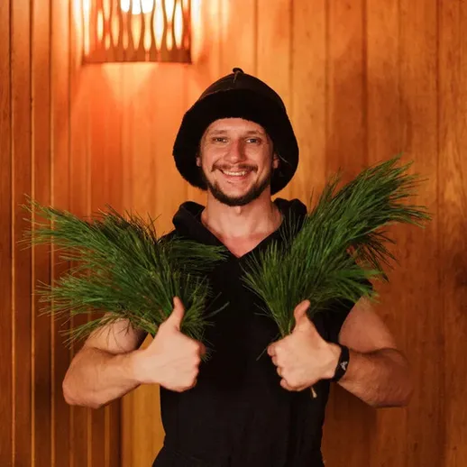 Человек с зелеными ветками в сауне в холодный зимний день