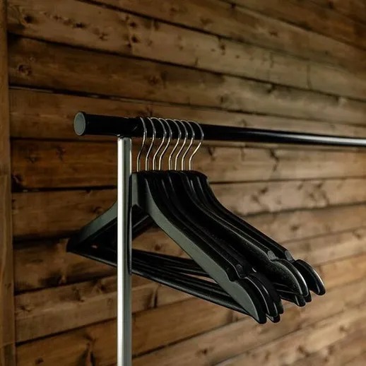 Вешалки для одежды на металлической перекладине в уютной комнате с деревянными стенами