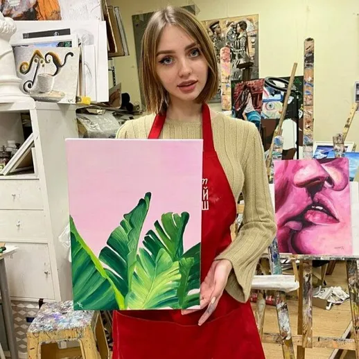 Молодая художница демонстрирует свою работу с зелеными листьями в художественной студии