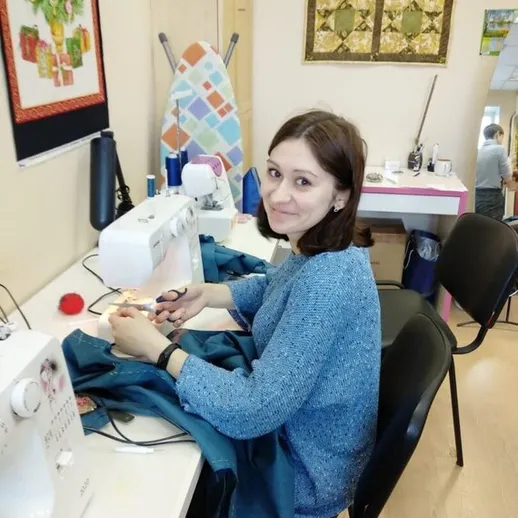 Женщина шьет одежду в уютной швейной мастерской