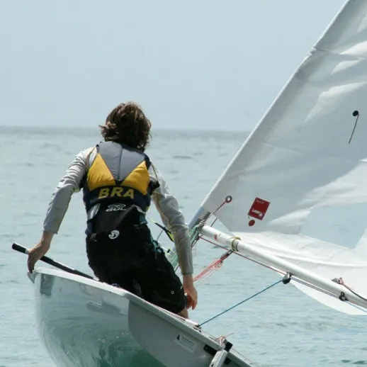 Парень управляет парусной лодкой у побережья в солнечный день на море