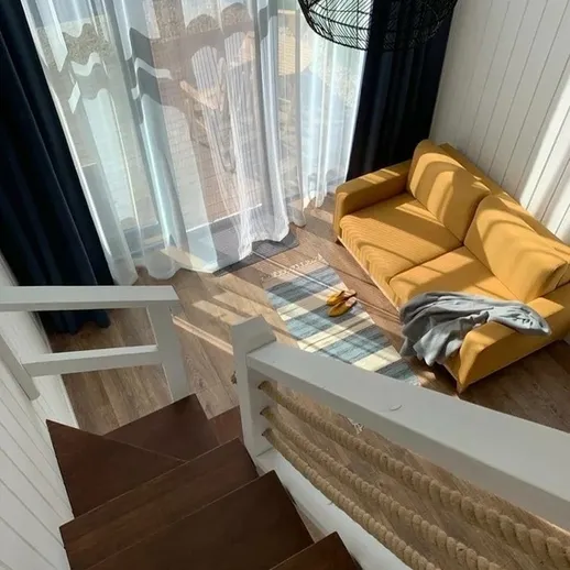 Уютная гостиная с желтым диваном и светлыми шторами в загородном доме