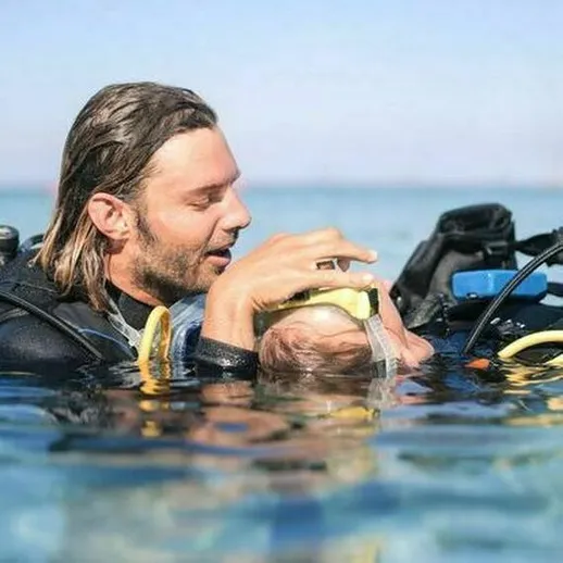 Подводное погружение в прозрачную воду: дайвер помогает новичку освоить снорклинг на берегу моря