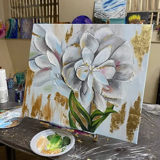 Картина в процессе создания с белыми цветами и золотыми акцентами в художественной студии