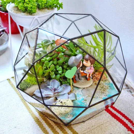 Миниатюрный сад в геометрическом террариуме с фигурками на столе в уютной комнате