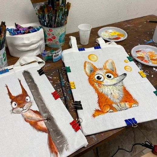 На столе художника готовятся картины с изображениями белки и лиса в уютной студии