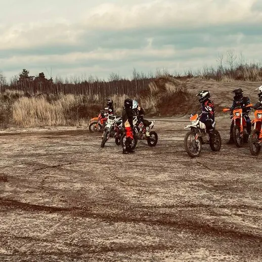 Группа мотоциклистов на мотокроссе в лесу, готовящихся к заезду в пасмурную погоду