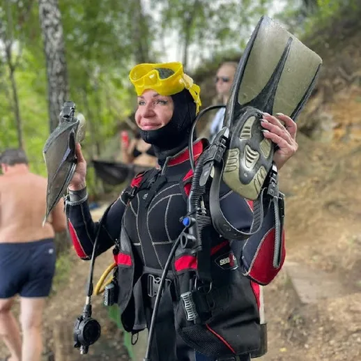 Женщина в снаряжении для подводного плавания с ластами на берегу водоема в теплый летний день