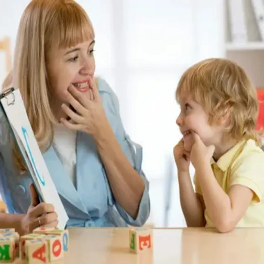 Учительница занимается с маленьким ребёнком в кабинете, помогая развивать навыки общения и обучения в уютной обстановке