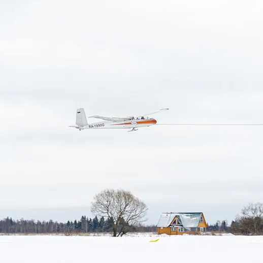 Летний самолет, пролетающий над сельским домом в снежный день, зимняя обстановка и спокойная атмосфера