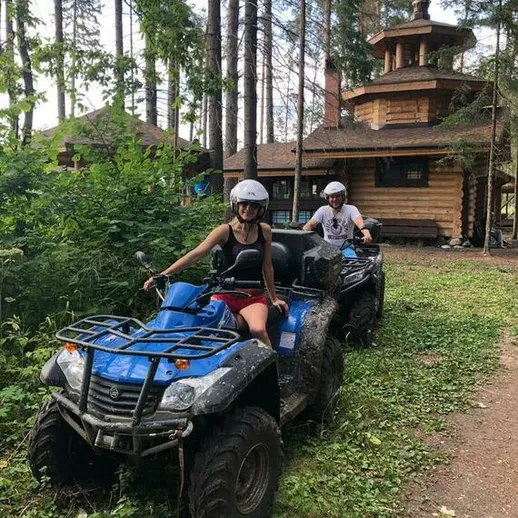 Два человека на квадроциклах наслаждаются природой в лесу неподалеку от деревянного дома