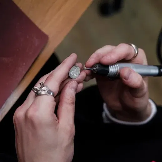 Ручная гравировка на металлическом изделии в мастерской, опытный мастер работает с инструментом