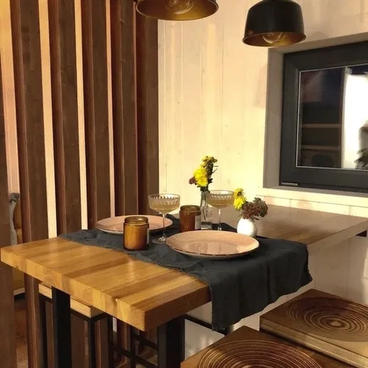 Уютный обеденный уголок с деревянным столом и стильными лампами в загородном доме