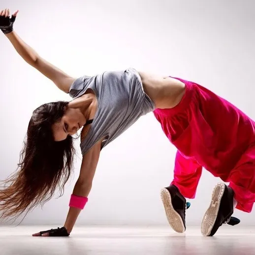 Девушка выполняет акробатические движения в яркой одежде на нейтральном фоне в студии