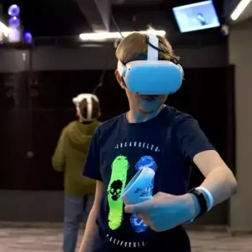 Мальчик с виртуальной реальностью в игровом центре, обучающийся управлению в симуляторе, вечернее время