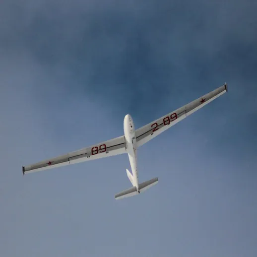 Самолет с длинными крыльями летит высоко в небе, захватывая внимание в ясный день