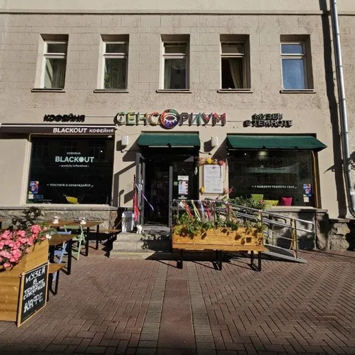 Кафе на улице с террасой и цветами в центре города в солнечный день