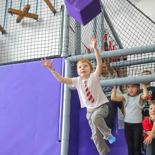 Дети играют в спортивном центре, прыгая и ловя кубик во время активного отдыха