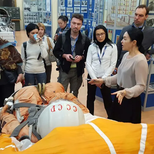 Группа людей слушает рассказ экскурсовода в космическом музее, образно преображая мир космических исследований