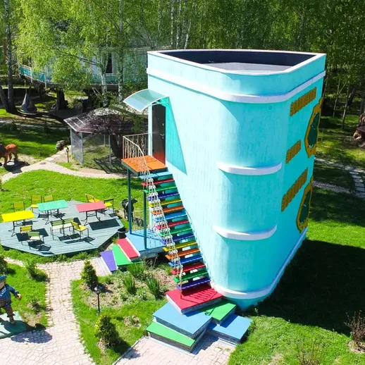 Оригинальный дом в форме книги в парке, окружённый зелёной Mustard, где посетители могут наслаждаться отдыхом на свежем воздухе