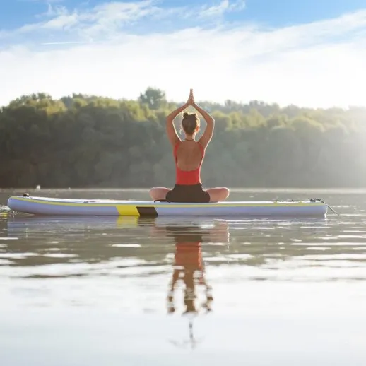 Женщина занимается йогой на SUP-борде на озере в солнечный день