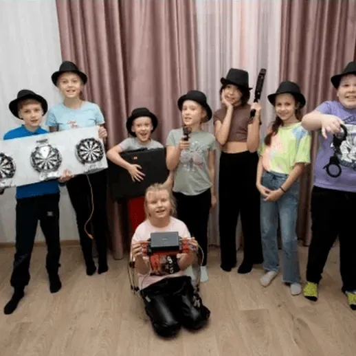 Группа детей с шарами для дартса и другими аксессуарами на вечеринке в комнате, где проходят игры и развлечения