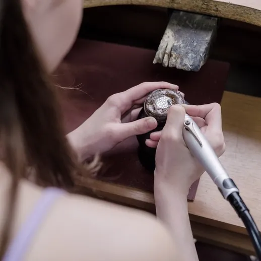 Мастер художественной гравировки работает над уникальными часами в своей мастерской в утренние часы